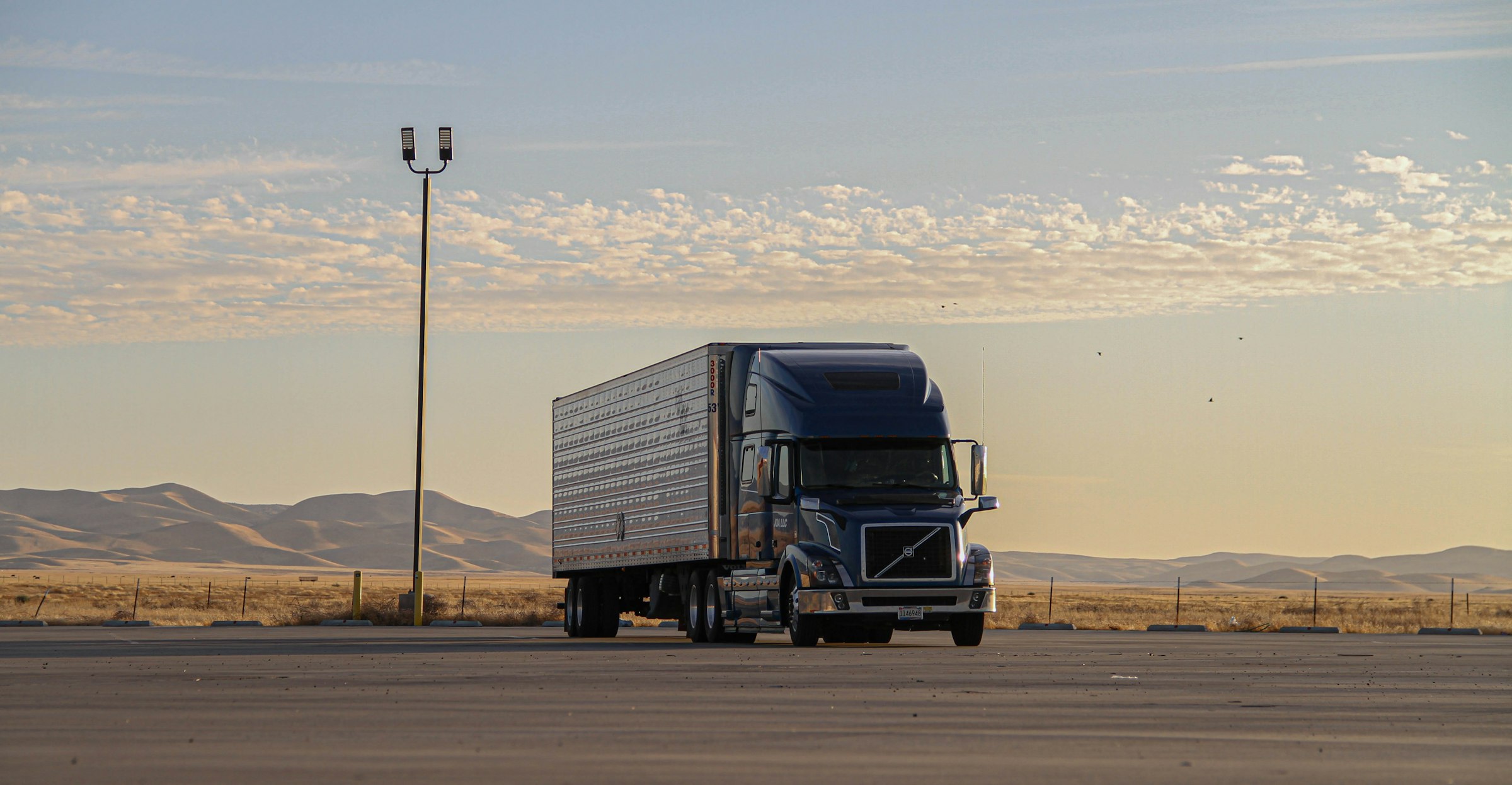 Semi truck and trailer on an open highway at dusk