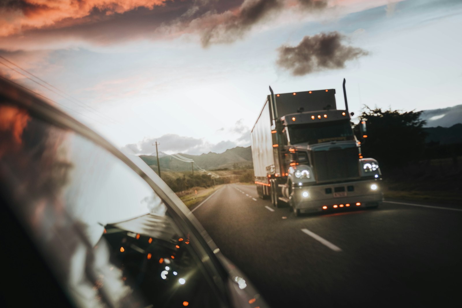 View from a truck's side mirror of another semi on the highway