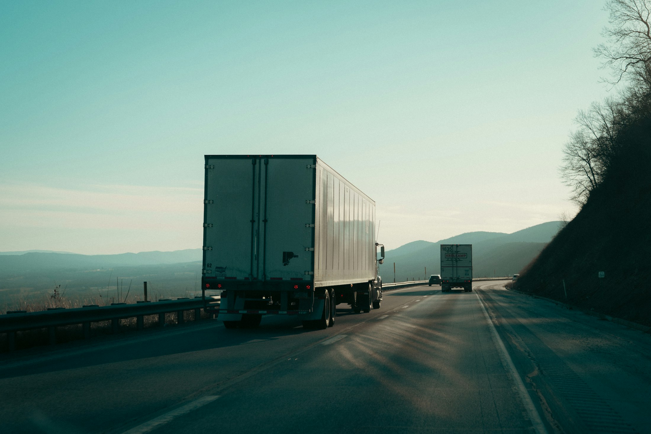 Two semi trucks on a highway at dawn